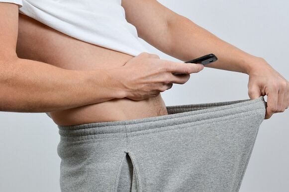 мъж гледа надолу по панталоните си към увеличен пенис